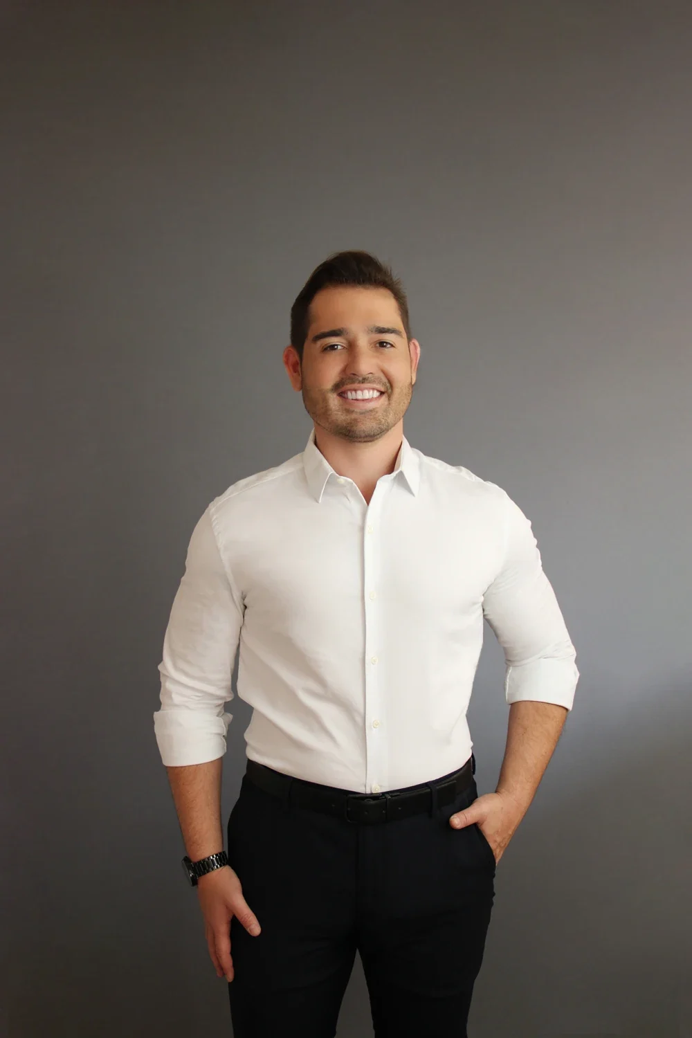 André Cherman, fundador da TOV Comunicação, de camisa branca, sorrindo, em retrato de estúdio com fundo cinza
